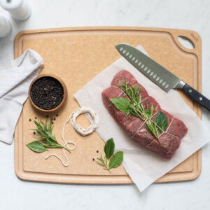 Sage cut board with knife and steak on it.