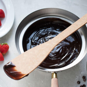 Sage Pro Stirring Tool on bowl of chocolate with strawberries.