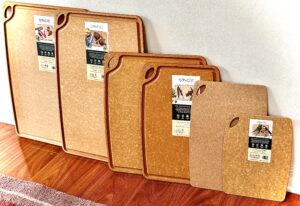 Sage carving and cutting boards in order of smallest to largest pictured against a white background and dark surface - four carving boards, two cutting boards. 